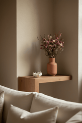 Ramo campestre assecat en tons rosats sobre una prestatgeria en un racó del saló